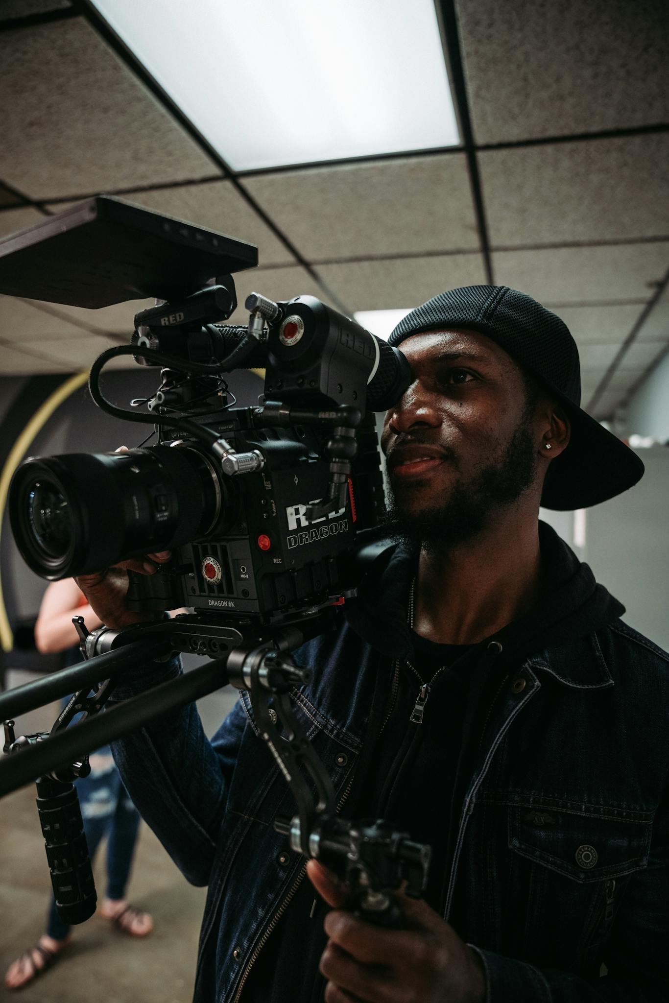 A skilled cameraman filming with a professional video camera in an indoor setting.