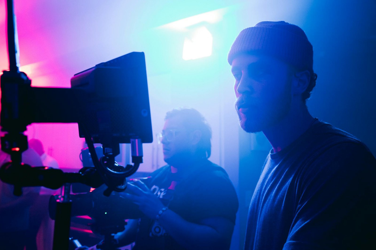 Film crew working under vibrant lighting setup on set, capturing dynamic scenes.